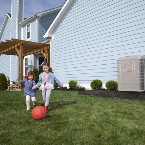 Children relaxing at home beside a Bryant Evolution thermostat